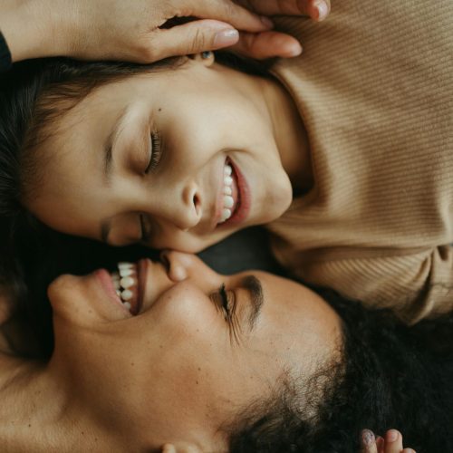 Close-up of a mother and daughter smiling joyfully, showcasing their playful bond and happiness.